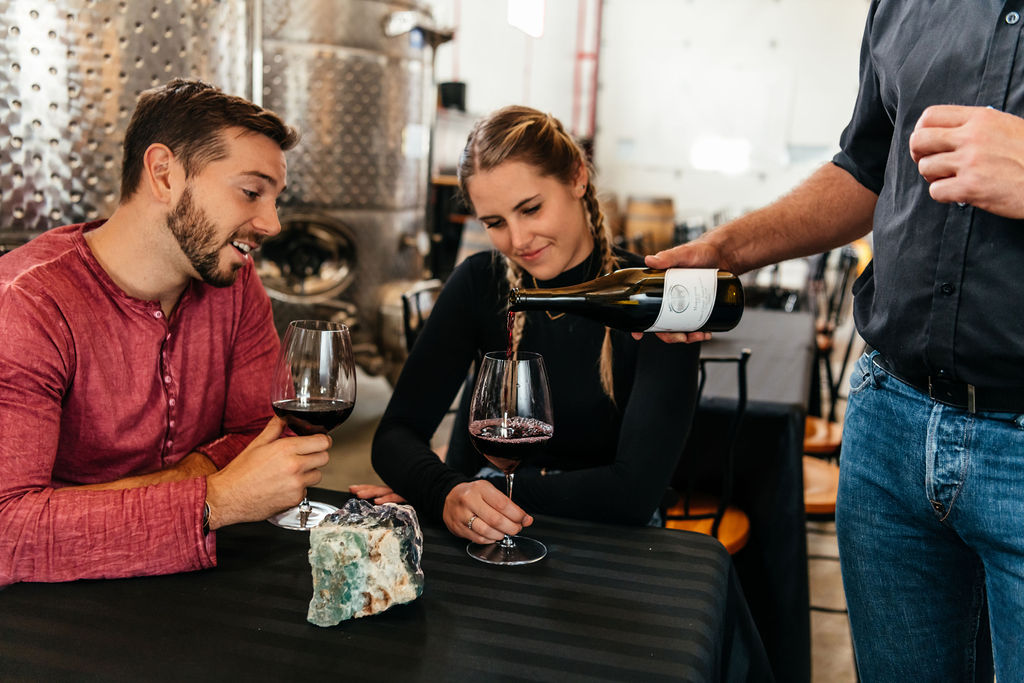 Two people at a table enjoying wine being served to them