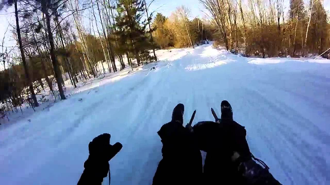 Person on a sled going down hill in the snow on a homemade luge track