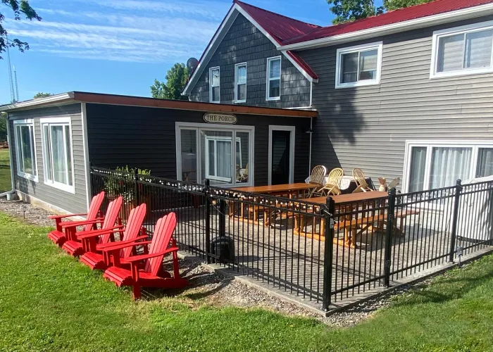 Exterior of Limerick Lake Lodge with four red Adirondack chairs overlooking Limerick Lake in Hastings County, Ontario